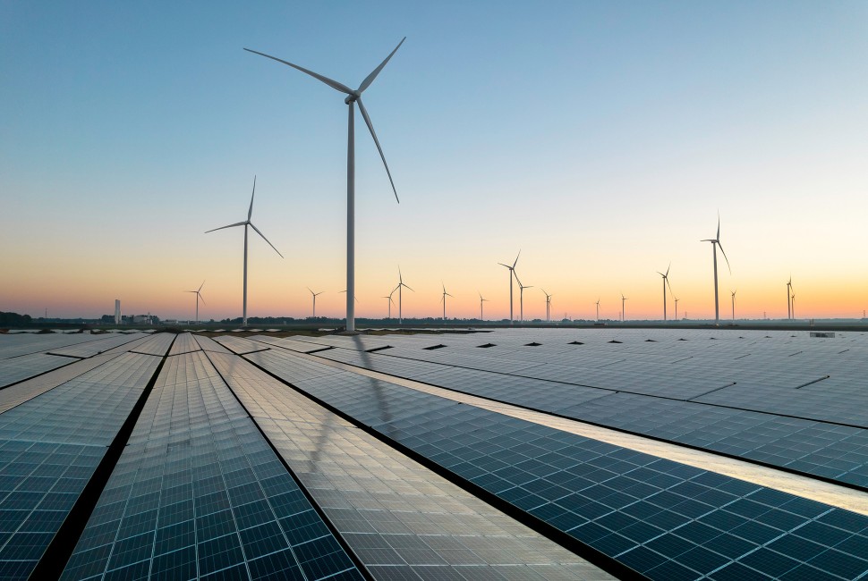 Solar panels with wind turbines in the background
